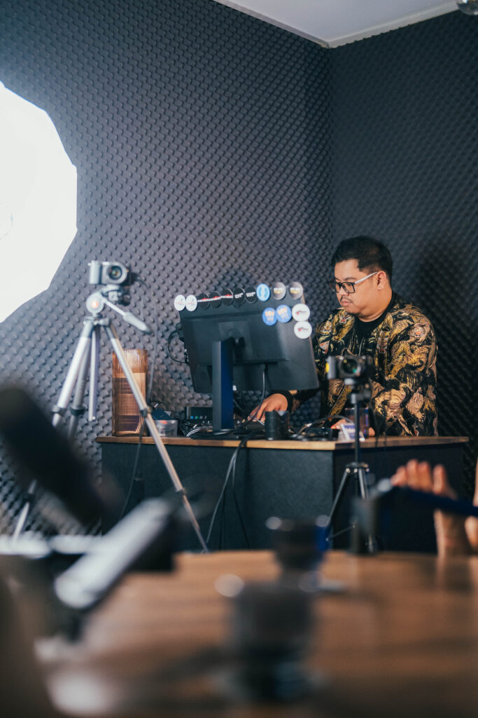 Producer working at the production desk surrounded by cameras and acoustic foam at Podwave Studios West Perth