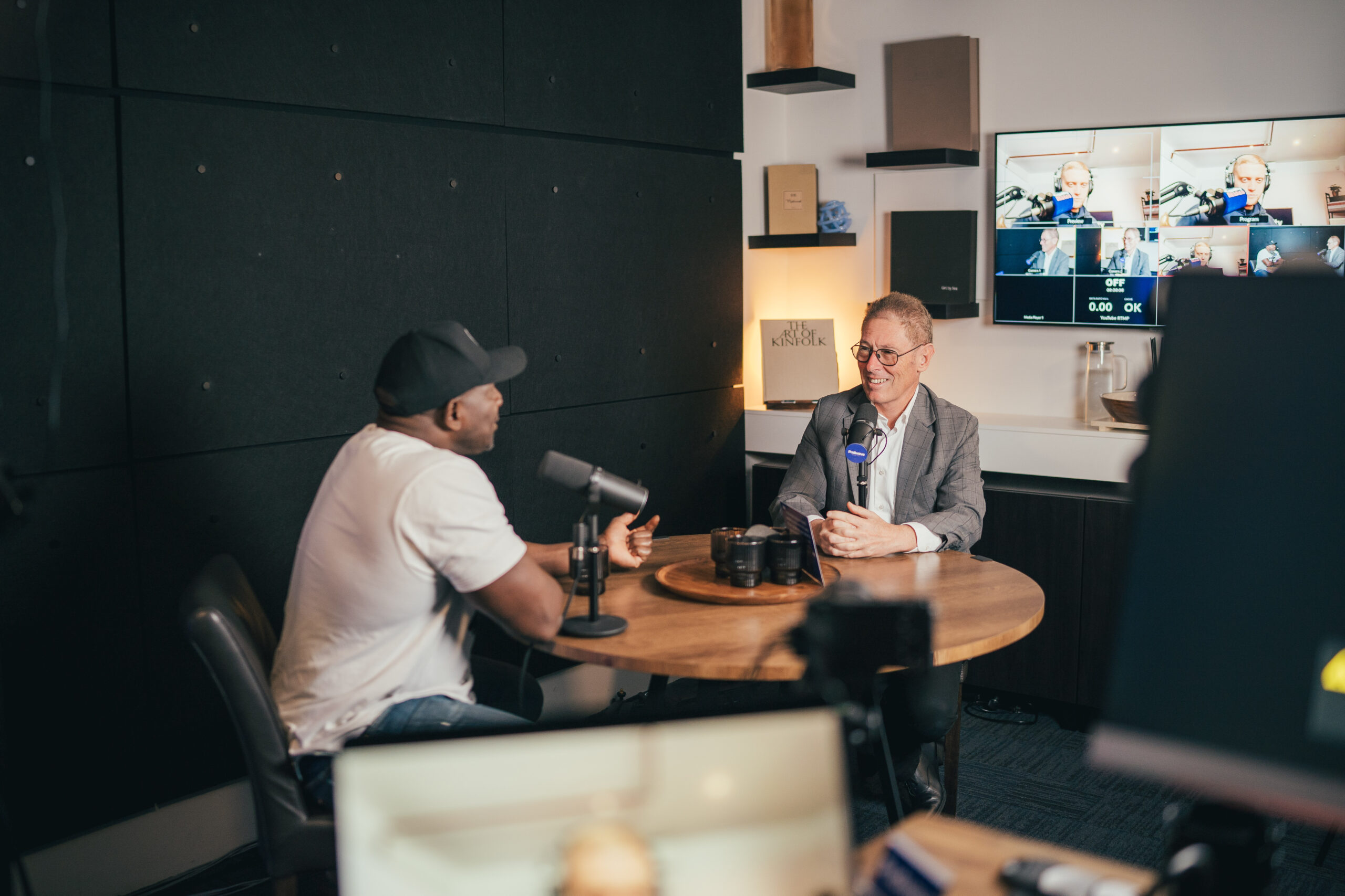 Dr Joe Kosterich and Tom in conversation at a round table with microphones recording a podcast at Podwave Studios West Perth with monitor in background